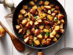 a pan filled with cooked potatoes on top of a wooden table next to an orange