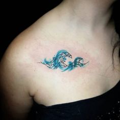 a woman with a tattoo on her chest has a blue wave in the shape of a dolphin