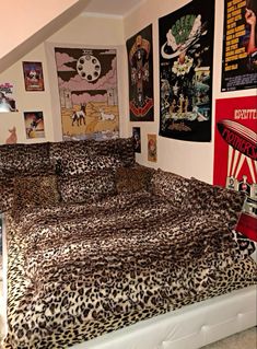 a leopard print comforter on a bed in a room with posters and pictures above it