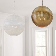 two large round lights hanging from the ceiling in a room with white walls and windows