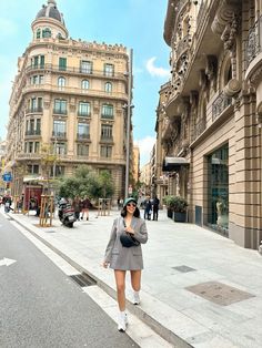 a woman is walking down the street talking on her cell phone and holding a purse