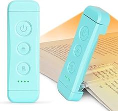 a blue remote control sitting next to an open book on top of a white surface