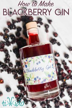 a bottle of blackberry gin sitting on top of a table next to some blackberries