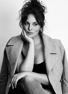 a black and white photo of a woman with her hand on her chin sitting down