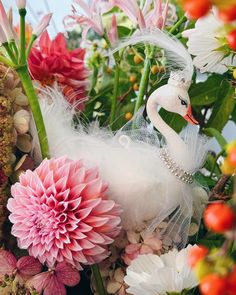 a white swan is surrounded by flowers and feathers