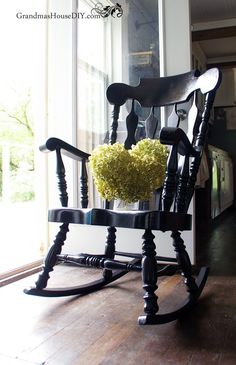 a rocking chair with a flower arrangement on the back and seat, in front of a window