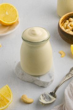 a jar of yogurt next to some sliced lemons and cashews