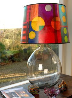 a lamp that is sitting on top of a table next to a book and magazines