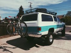 a white and blue van with a bike on the roof rack in front of it