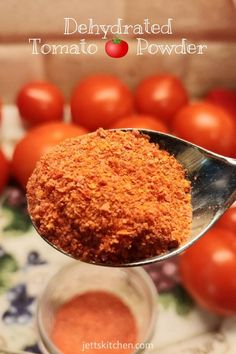 a spoon full of tomato powder with tomatoes in the background