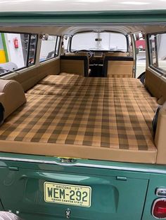 the back end of an old green truck with a checkered blanket on it's bed