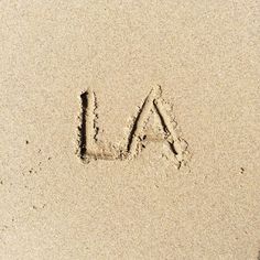 the word la is written in sand with an arrow drawn on it's side