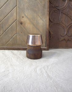 a metal container sitting on top of a white blanket next to a wooden door and wall