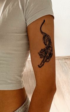 a woman with a tiger tattoo on her left arm and right arm behind her back