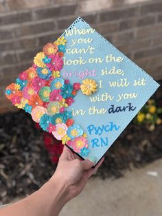 someone holding up a graduation cap with flowers on it that says, when you can't look on the bright side, we will hit in the dark