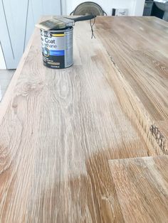 a can of paint sitting on top of a wooden table next to a white cabinet