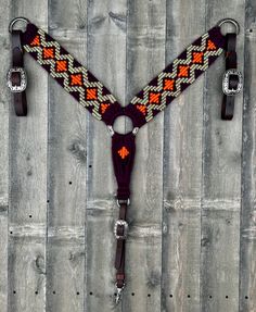 a pair of horse bridles with matching straps on wooden boards, one has an orange and blue design