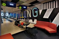 a bowling alley with red couches and black tables in the center, along with neon lights