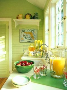 a kitchen counter topped with bowls filled with fruit and juice next to a window covered in shutters