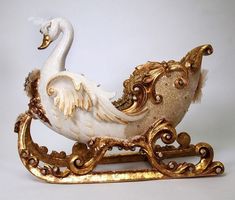 a white swan sitting on top of a sleigh with gold trimmings