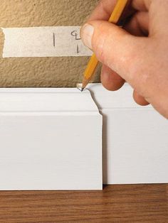 a person holding a pencil in front of a piece of paper on top of a wooden table