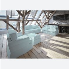 a living room filled with white furniture next to a fire place in a loft style building