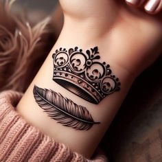 a woman's wrist tattoo with a crown and feather