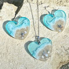 two heart shaped glass pendants sitting on top of a stone slab next to each other