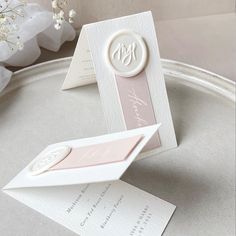 a white and pink wedding card on top of a table next to a vase with flowers