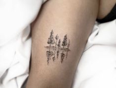 a woman's arm with trees and water tattoo on the left side of her body