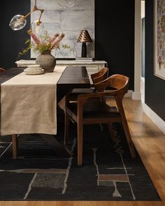 a dining room with black walls and wooden chairs