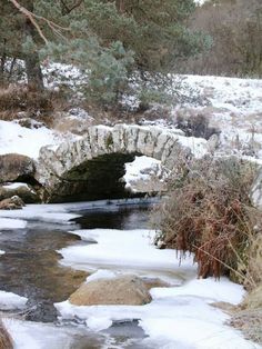 a stone bridge over a small stream in the snow