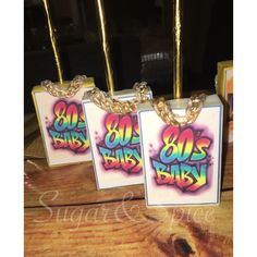 three small tags with the words 80's baby on them are hanging from chains