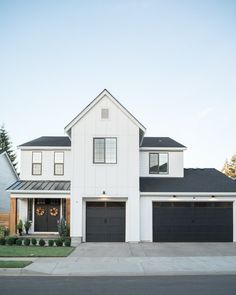 a large white house with two garages on the front and one car door open