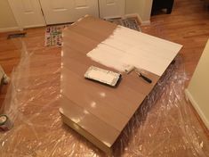 a cardboard box sitting on top of a hard wood floor covered in plastic and tape