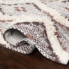 a brown and white rug laying on top of a wooden floor