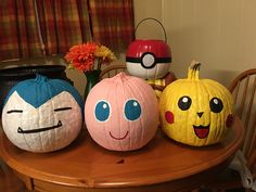 four pumpkins with faces painted on them sitting on a table