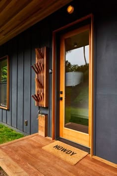 a wooden bench sitting in front of a door on the side of a house next to a grass covered yard