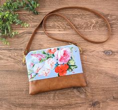 "This small crossbody bag is perfect for everyday. Just the right size to carry all of your essentials hands free without weighing you down. A great addition to your wardrobe. Vintage Floral Cross-Body Bag: Flower bag, faux leather ~This beautiful bag is made with a beautiful vintage floral print.  Featuring a periwinkle blue background with various pink and orange blossoms.  ~The bottom of the bag is made with quality vegan(cruelty free) leather in a nice warm toffee brown color. ~Entire bag is lined with a light interfacing to add durability to the bag. ~Bag is securely closed with a brass metal ykk zipper. ~Interior of the bag is lined with a heavy black canvas that will hold up well to messes, and wear and tear. ~One inside zipper pocket.  ~Long removable vegan leather strap is attache Floral Print Crossbody Shoulder Bag For Everyday Use, Everyday Floral Print Crossbody Shoulder Bag, Spring Crossbody Bag With Zipper Pouch, Spring Crossbody Shoulder Bag With Cell Phone Pocket, Spring Crossbody Shoulder Bag With Zipper Pouch, Spring Shoulder Bag Zipper Pouch For Everyday Use, Spring Everyday Zipper Pouch Shoulder Bag, Spring Shoulder Bag With Zipper Pouch For Daily Use, Spring Everyday Shoulder Bag With Zipper Pouch