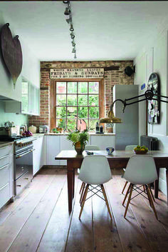 a kitchen with wooden floors and white walls, along with an island table surrounded by chairs