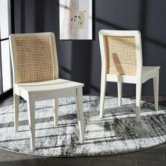 two white chairs sitting on top of a rug