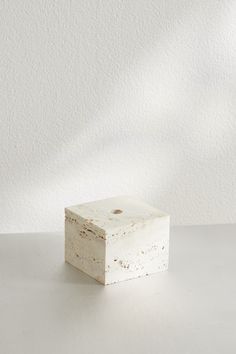 a white square object sitting on top of a table next to a vase with flowers in it