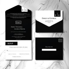 an elegant black and white wedding suite is displayed on a marble surface with the initials e g