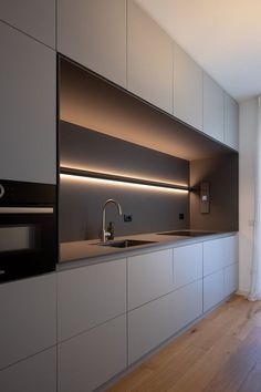 a modern kitchen with white cabinets and stainless steel appliances, along with wood flooring