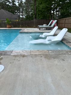 an empty swimming pool with lounge chairs next to it