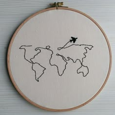 an embroidered world map with a plane flying over the top, on a white background