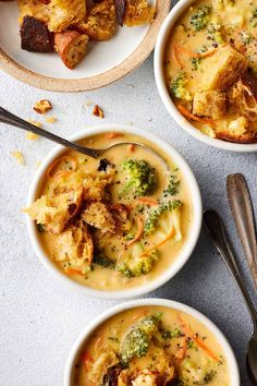 three bowls filled with soup and bread on top of a table