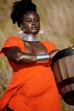 a woman in an orange dress holding a barrel