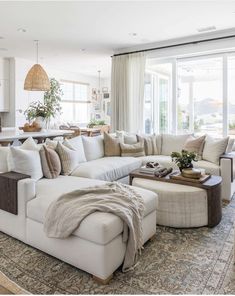 a living room filled with white furniture and lots of pillows on top of it's couches