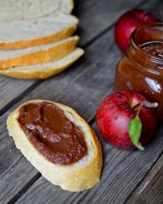 an apple and peanut butter sandwich on a wooden table next to some apples, jam and bread